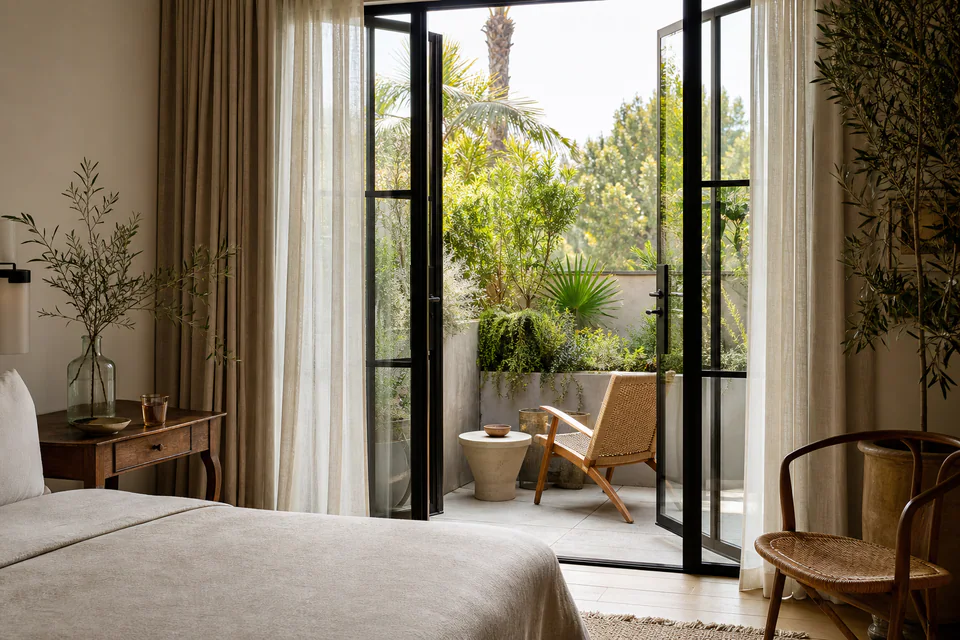 Warm guest room opening onto a leafy terrace